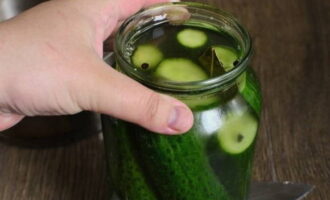 Pour hot brine over the cucumbers. Leave them to cool and salt at room temperature. After two days, the vegetables will change color and will be completely ready. Store them in the refrigerator.