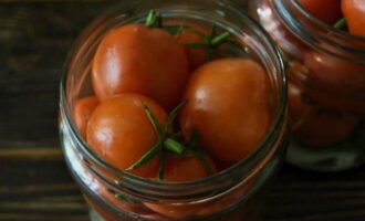 Letakkan tomato yang telah dibasuh dan dicucuk dengan ketat di sini. Letakkan biji lada dan daun bay di atas dan tuangkan air mendidih selama 20 minit. Selepas itu, toskan air dan masukkan perapan manis. Untuk itu, masak air dengan gula dan garam, dan akhir sekali masukkan cuka. Kami menutup bahan kerja dengan tudung, terbalikkannya, bungkusnya dalam selimut dan biarkan sehingga ia sejuk sepenuhnya.