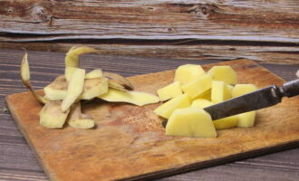 Mentrestant, peleu les patates i talleu-les a trossos. Traieu la capa superior de ceba i piqueu-la. Saltejar amb una petita quantitat d'oli vegetal.