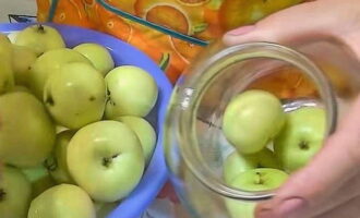 Place the apples in clean jars. First we put the large fruits, then the smaller ones.