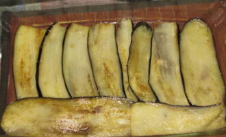 Fry the eggplants in a heated frying pan in vegetable oil for two minutes on each side. Then place them in a baking dish.