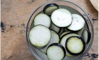 Misture água com sal e coloque as rodelas de berinjela na solução resultante. Após 30 minutos, escorra a água e seque os vegetais com guardanapos de papel dos dois lados.