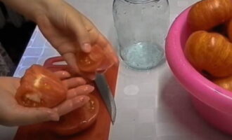 Escurrir el agua caliente. Retire con cuidado la piel de cada tomate de la base del tallo, córtelo en rodajas según el tamaño y colóquelo de forma compacta en tarros limpios de un litro.