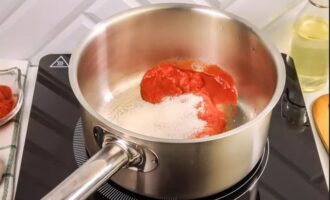 Coloque la pasta de tomate en una cacerola o cacerola. Agrega azúcar y sal y sofríe mientras revuelves durante 5 minutos a fuego medio.