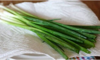 Spread a cotton towel on the table and place the washed onion feathers on it in one layer. Leave the onions for a while so that all the moisture evaporates.