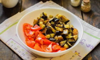 Doe de gebakken aubergines in een slakom en laat iets afkoelen. Voeg er vervolgens gehakte tomaten aan toe.