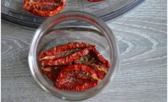 Sterilizziamo i barattoli, aggiungiamo i pomodori secchi, cospargendo gli strati con le spezie.