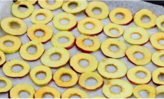 Coloque los aros de manzana en una bandeja para hornear forrada con papel pergamino. Establece la temperatura mínima en la estufa de gas.