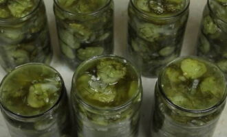 Place the prepared winter salad of cucumbers, onions and butter into jars.