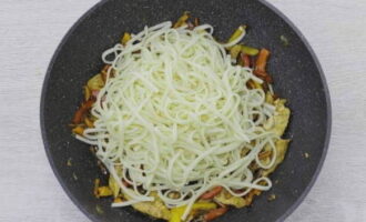 Agrega los fideos udon hervidos a las verduras y el pollo, mezcla bien y cocina el plato a fuego lento durante otros 2-3 minutos para que la salsa sature los fideos.