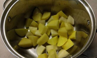 Sbucciare le patate, lavarle, tagliarle a pezzi grossi e trasferirle subito in una casseruola per stufare.