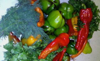 We prepare the components. Take a generous bunch of dill, parsley and cilantro. Soak in water to remove dirt. Rinse. Rinse and wipe hot peppers and bell peppers. Divide the garlic heads into cloves and peel them.