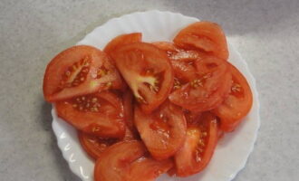 Scald the tomatoes and remove their skins. Then cut into rings or half rings.