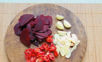 We cut the peeled beets into slices, the garlic into slices, and cut the hot pepper directly with the seeds into rings.