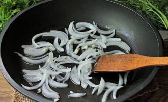 Rozgrzej olej roślinny na patelni i smaż półpierścienie cebuli i drobno posiekany czosnek przez około 3 minuty na umiarkowanym ogniu.