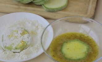 Roer opnieuw goed, dompel de plakjes courgette in het eimengsel en rol ze vervolgens door de bloem. Voor een betere hechting herhaalt u de procedure tweemaal.