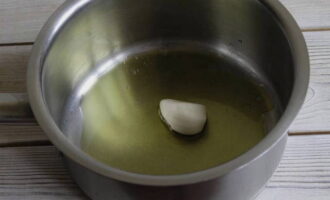 Pour olive oil into a thick-bottomed saucepan. Then place the peeled garlic clove on the heated oil and fry it for 1-2 minutes. Garlic is needed only to make the oil fragrant. Then you can throw it away.