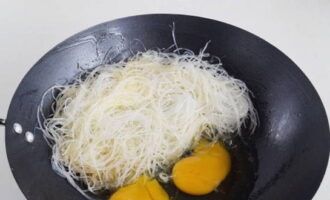 Drain the rice noodles. Then put it in a wok and break the chicken eggs. When the eggs have set a little, stir them into the noodles.