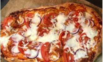 Coat the golden brown base with grated tomatoes. Place chopped fresh tomatoes, onions, and grated soft cheese here. Bake for another 6 minutes.