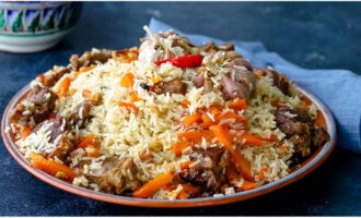 Classic Uzbek pilaf in a cauldron on the stove is ready. Place on plates and serve a hearty dish to the table!