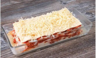 Apabila semua lapisan dipasang, letakkan kepingan lasagna di atas, tuangkan sos bechamel di atas dan taburkan dengan baki keju.