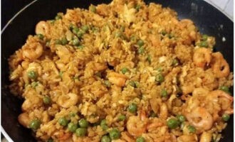 Fried rice with shrimp in a frying pan is ready. Serve with green onions and sesame seeds. 