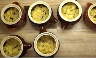 Prepare the pots. Peel the potatoes, rinse them, cut them into small cubes and place them in pots. Then pour a tablespoon of oil and 50 ml of water into them.