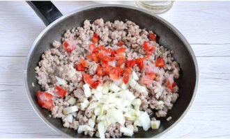 Skrell løken og hakk den. Skjær de vaskede tomatene og paprikaen i terninger. Vi laster av de hakkede grønnsakene på den stekte kjøttdeigen. Etter omrøring, kok i 7 minutter.