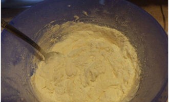 Pour in the flour and baking powder, previously sifted through a sieve. Stir, breaking up lumps.