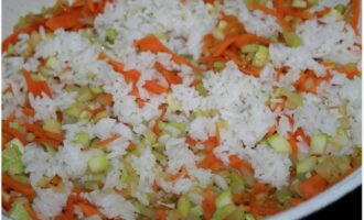 Having freed the garlic cloves from the husks, chop them and add them together with the rice to fry. Fry with regular stirring for a couple of minutes.