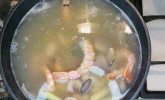 15 perc elteltével adjuk hozzá a tom yum pasztát, a gombát, a garnélarákot és a halszószt.