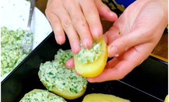 Place the halved potatoes on a greased baking dish. We distribute the fragrant filling on top.