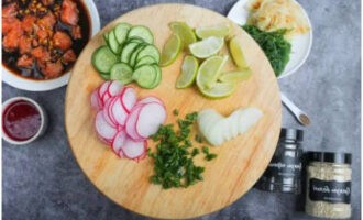 Cut the lime into wedges. Cut the cucumber, radish and white onion into thin slices. Finely chop the green onion with a knife.