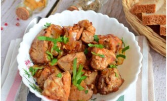 Fertig sind gebratene Schweinefleischstücke mit Zwiebeln in einer Pfanne. Mit Gemüse garniert auf den Tisch servieren!