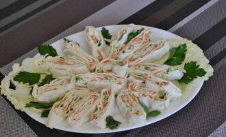 Lavash yang disumbat dengan keju dadih dan ikan merah sudah siap. Potong pembuka selera dan letakkan di atas pinggan dengan daun kubis Cina, dihiasi dengan herba segar.