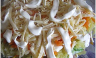 Bestrooi de salade vervolgens met geraspte kaas en bestrijk deze met mayonaise.