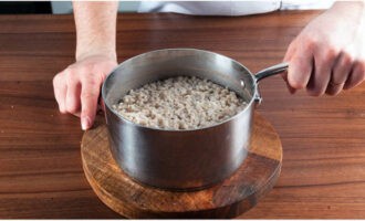 How to cook rassolnik according to the classic recipe with barley and pickles? First fill the pearl barley with cold water for 3 hours. Then drain the water and transfer the pearl barley into a saucepan. Pour 600 ml of water into it, put it on the fire and cook for 40 minutes after boiling.