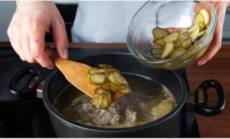 Add prepared pearl barley and pickles here, add salt and ground pepper to taste. Cook for 10 minutes over low heat. Then turn off the fire and keep the workpiece under the lid.