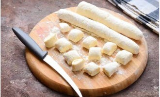 Produciamo piccole salsicce dall'impasto. Tagliateli con un coltello in pezzi di uguale spessore.