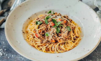 Klassieke Bolognese pasta met gehakt in een koekenpan is klaar. Serveer, gegarneerd met geraspte kaas en kruiden.