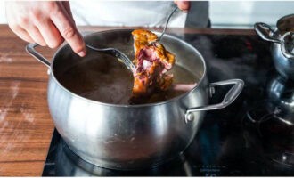 Coupez les côtes de porc en plusieurs petits morceaux. Placez la viande dans une grande casserole et versez environ 2 à 2,5 litres d'eau. Placez le récipient sur le feu et portez l'eau à ébullition. Retirez la mousse de la surface du bouillon et réduisez légèrement le feu, faites cuire le bouillon pendant environ 1 à 1,5 heures. La viande des côtes doit devenir molle.