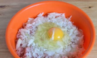 Add chopped onions to the meat and break one chicken egg.