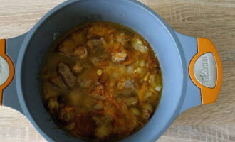 Place the roasted beef and vegetables into a thick-walled pan. Pour in hot water to cover the contents of the container, salt and season the meat to taste.