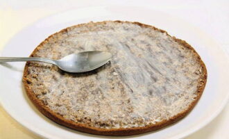 Iniziamo ad assemblare: adagiamo uno strato di torta sul fondo di un piatto da portata e immergiamolo in un composto di panna e acqua.