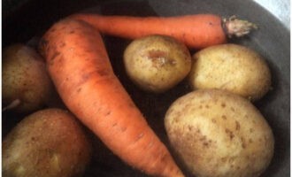 Was de wortels en aardappelen goed. Doe het in een pan met water en zet in brand. Zet na het koken het vuur laag tot matig. Kook een derde van een uur. Nadat u de gereedheid heeft gecontroleerd, laat u het water weglopen en laat u de groenten afkoelen.