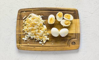 Boil and peel chicken eggs. Finely chop four eggs with a knife, cut the rest into halves. They will come in handy for serving.