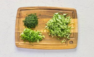 We wash the cucumbers and grate them on a coarse grater. Wash the greens, dry and finely chop.