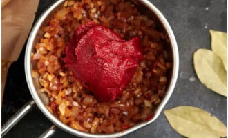 Add chopped cilantro stems and adjika to the vegetables. After 3 minutes, add tomato paste. Cook for about 25 minutes, stirring occasionally.