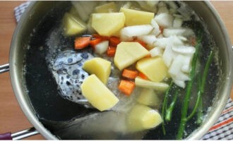 Place the remaining pieces of fish into the boiling base. Throw in the chopped vegetables and washed dill stalks or umbrellas.