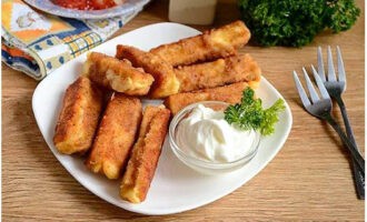 I bastoncini di formaggio in una padella a casa sono pronti. Servire in tavola!